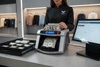 Retail employee using a bill counter machine to count U.S. currency while reconciling a cash drawer at a store register, with counterfeit detection and cash management features displayed.